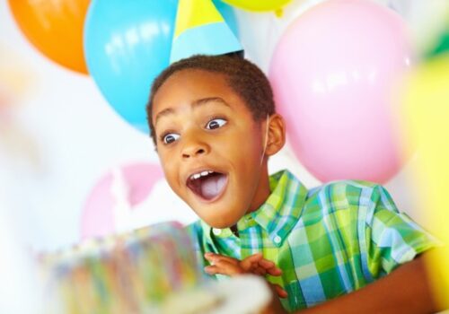 Kid Smiling Behind a Cake, Enjoying Birthday Parties for East Peoria IL