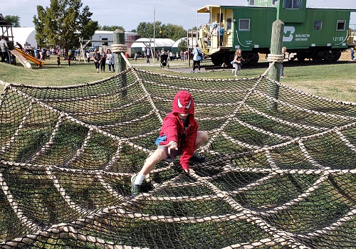 A boy sits in a spider web wearing a spider man jacket while playing at Tanners Orchard, which offers Family Activities for Morton IL residents