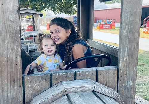 Sisters sit in a structure at Tanners Orchard, an unforgettable Event Venue by Morton IL