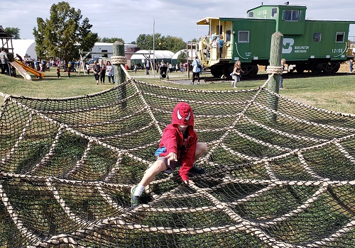 A child dressed as Spiderman plays in a web structure at Tanners Orchard, an Event Venue by Washington IL