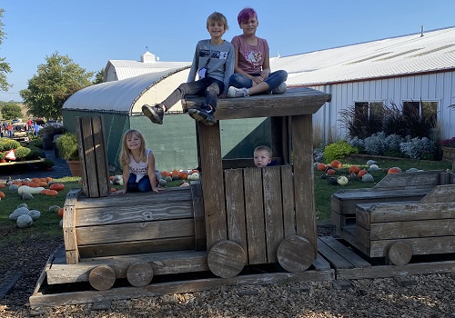 A group of children play and pose on a train found at Tanners Orchard, an Event Venue near Pekin IL
