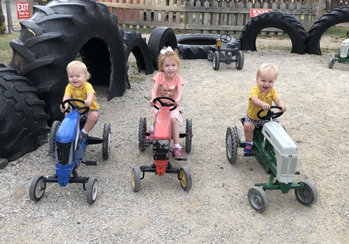 Kids ride on small tractors at Tanners Orchard, which is a fun Event Venue by Bloomington IL