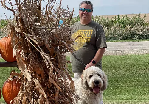 A man poses with his dog at Tanner's Orchard, an Apple Orchard by Champaign IL