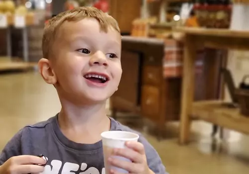 A toddlers smiles while drinking apple juice. There are many Health Benefits of Apples.