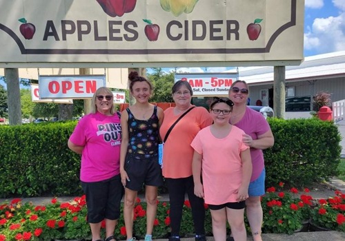 A family stands in front of a Tanners Orchard, which offers the Best Apple Picking in Illinois