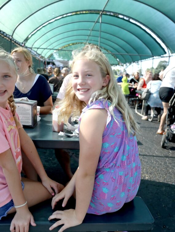 Two smiling girls enjoying a meal at Tanners Orchard