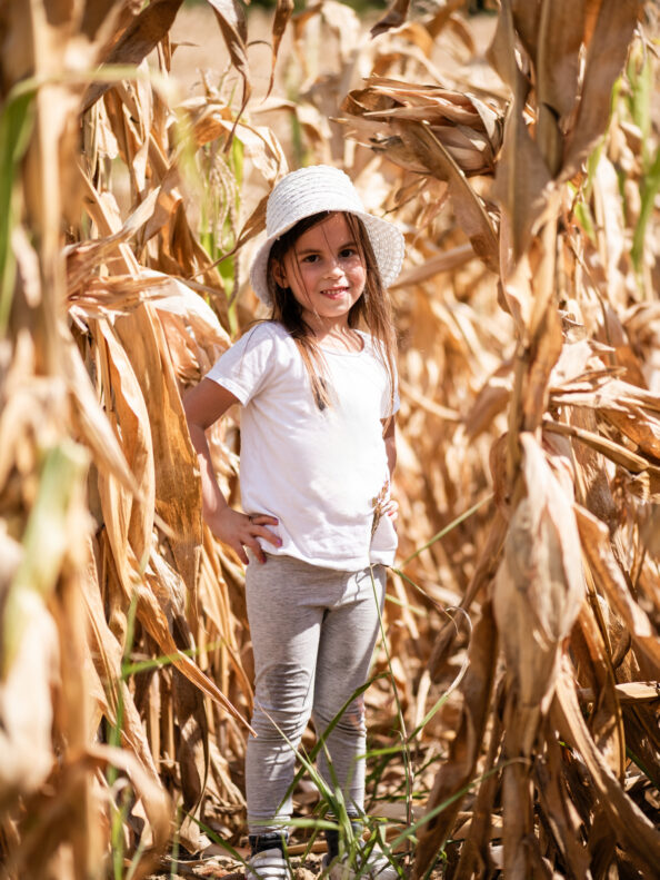 a happy girl standing in a field of corn at Tanners Orchard